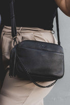 woman carrying a black leather crossbody bag