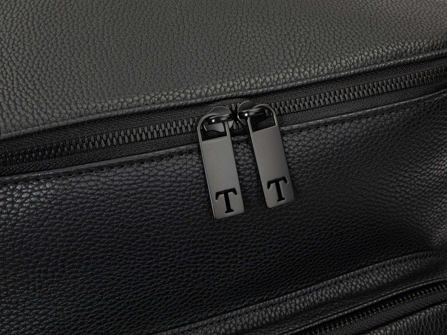 Close-up of the two black zippers on a black leather nappy backpack.