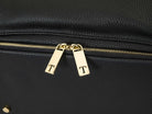 Close-up shot of two gold zippers on a black leather nappy backpack from Tottie