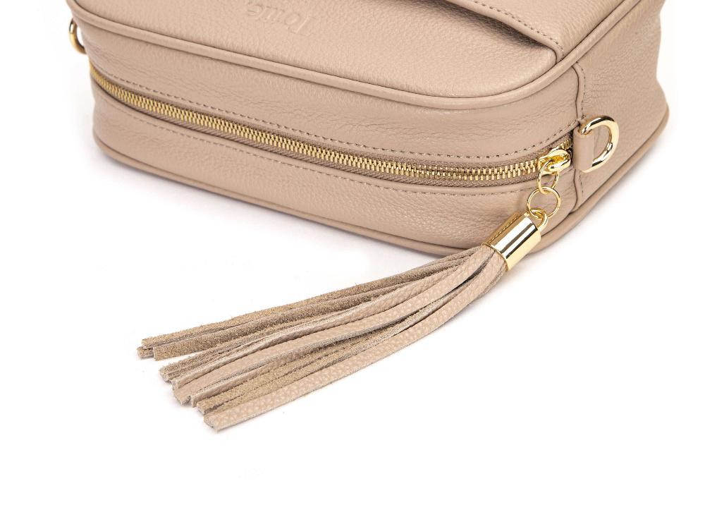 A close-up of a stone leather tassel attached to a gold-toned ring on a stone handbag from Tottie