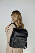 Woman facing away, wearing a black nappy backpack with a black zipper from Tottie.