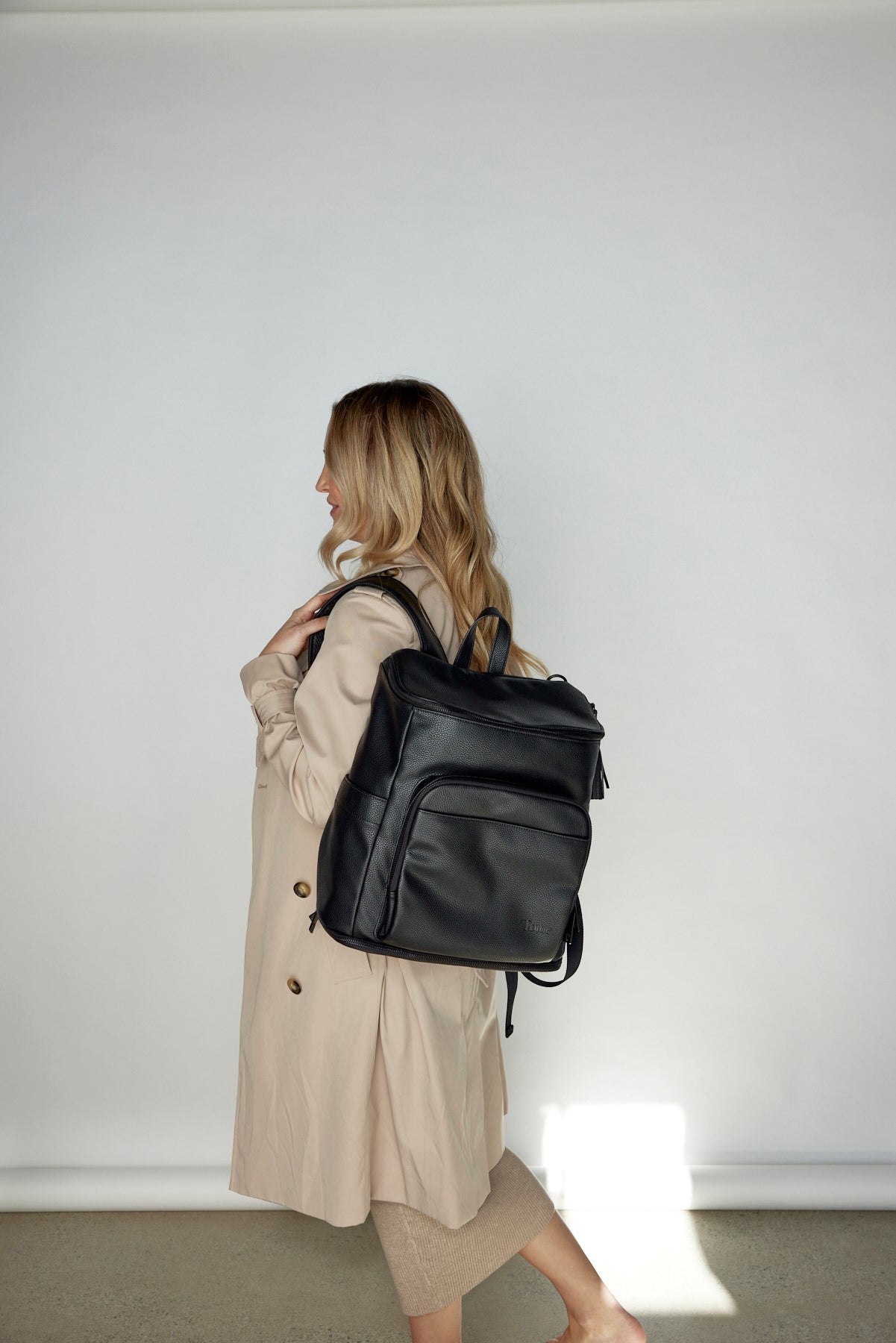 Woman carrying a black leather nappy backpack over her shoulder