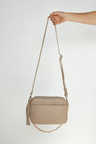 Woman Holding Bestie Stone Leather Crossbody Bag with Gold Chain Strap and Tassel from Tottie