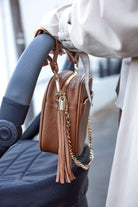 Black stroller with Tottie's tan pram clips attached to a tan crossbody bag from Tottie.