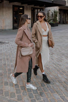 Two women walking down the street, each carrying a Bestie Crossbody Bag from Tottie—one in stone color and the other in tan